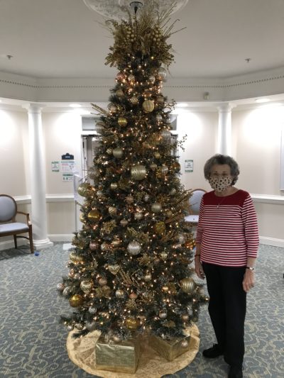 Senior resident in front of Christmas tree